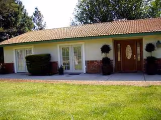 Single-story building exterior with a front door, windows, and manicured shrubs.