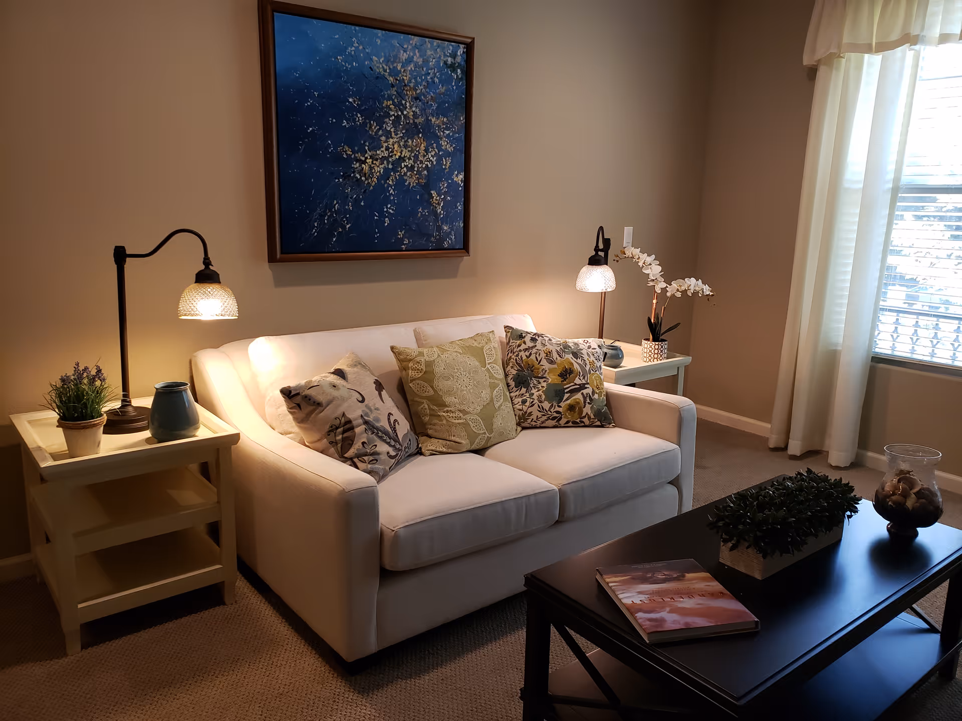 Cozy living room scene with sofa, lamps, plants, and a window in Oakmont of Concord