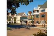 Front exterior of a multi-story senior living community building with a covered entrance, driveway, and landscaping.