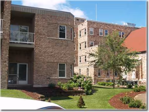 Exterior brick building of Bell Tower Residence Assisted Living with manicured lawn and trees