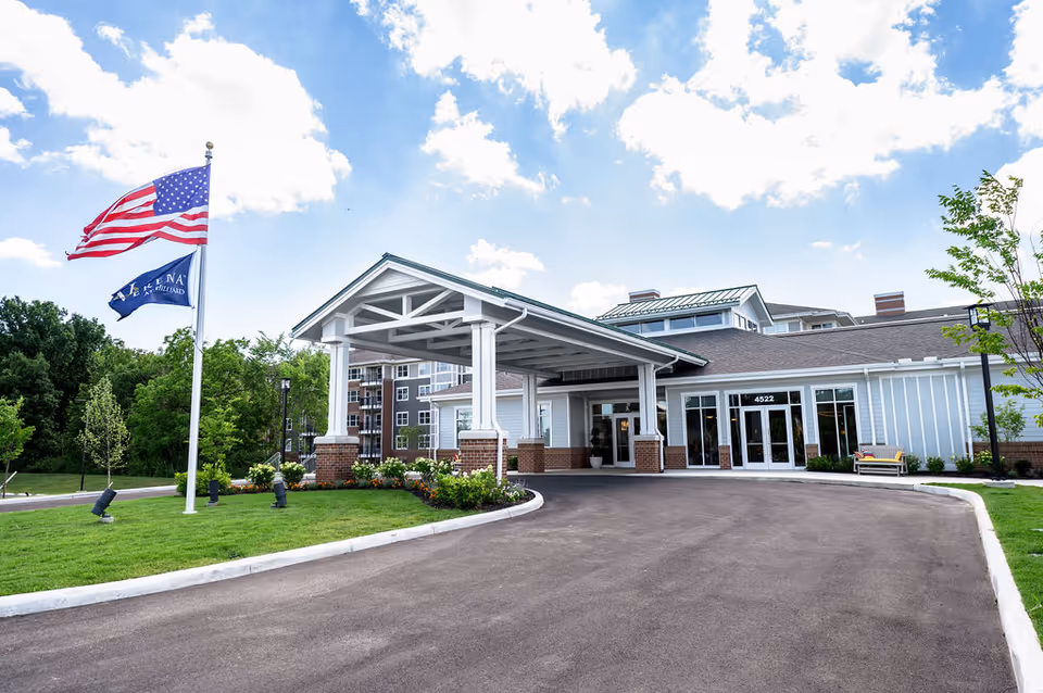 Verena at Hilliard entrance with porte-cochère and flags by curved driveway.