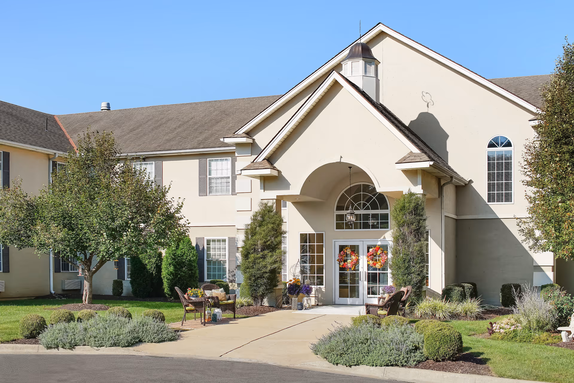 Exterior view of The Goldton at Athens, with arched entrance, landscaping, and seating areas.