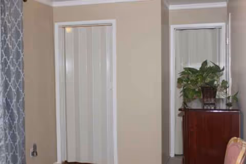 Beige hallway with two white doors, a wooden cabinet, and a potted plant.