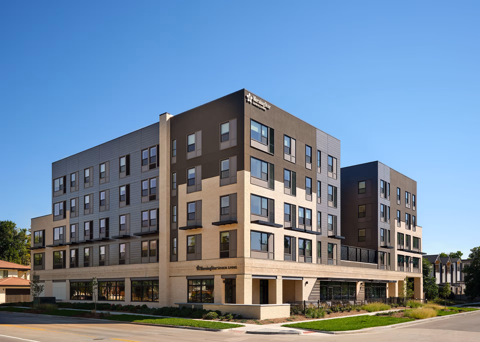 Modern multi-story senior living building with brick and gray siding.