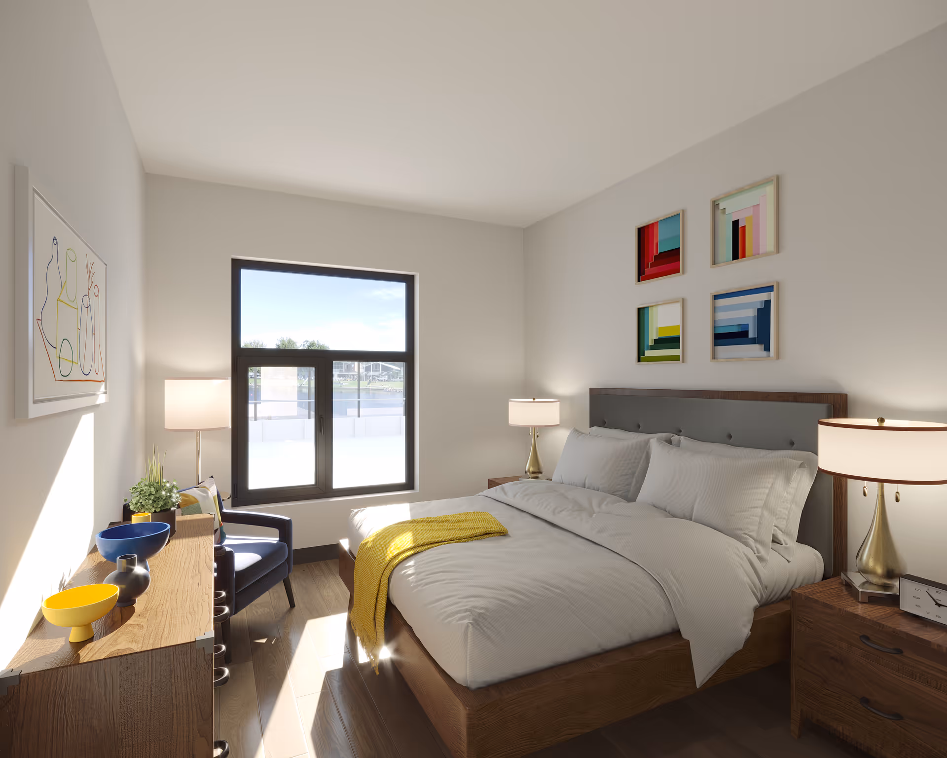 A bright, modern bedroom with a large window letting in natural light. The room features a wooden bed with white bedding and a yellow throw blanket, two bedside tables with lamps, a wooden dresser with decorative bowls and a plant, a blue armchair, and colorful abstract artwork on the walls.
