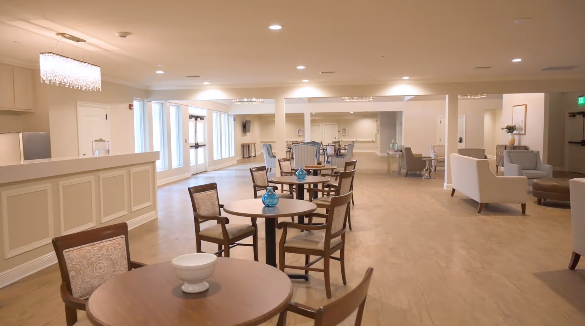 Spacious, well-lit communal dining and lounge area with round tables, chairs, and seating nooks.