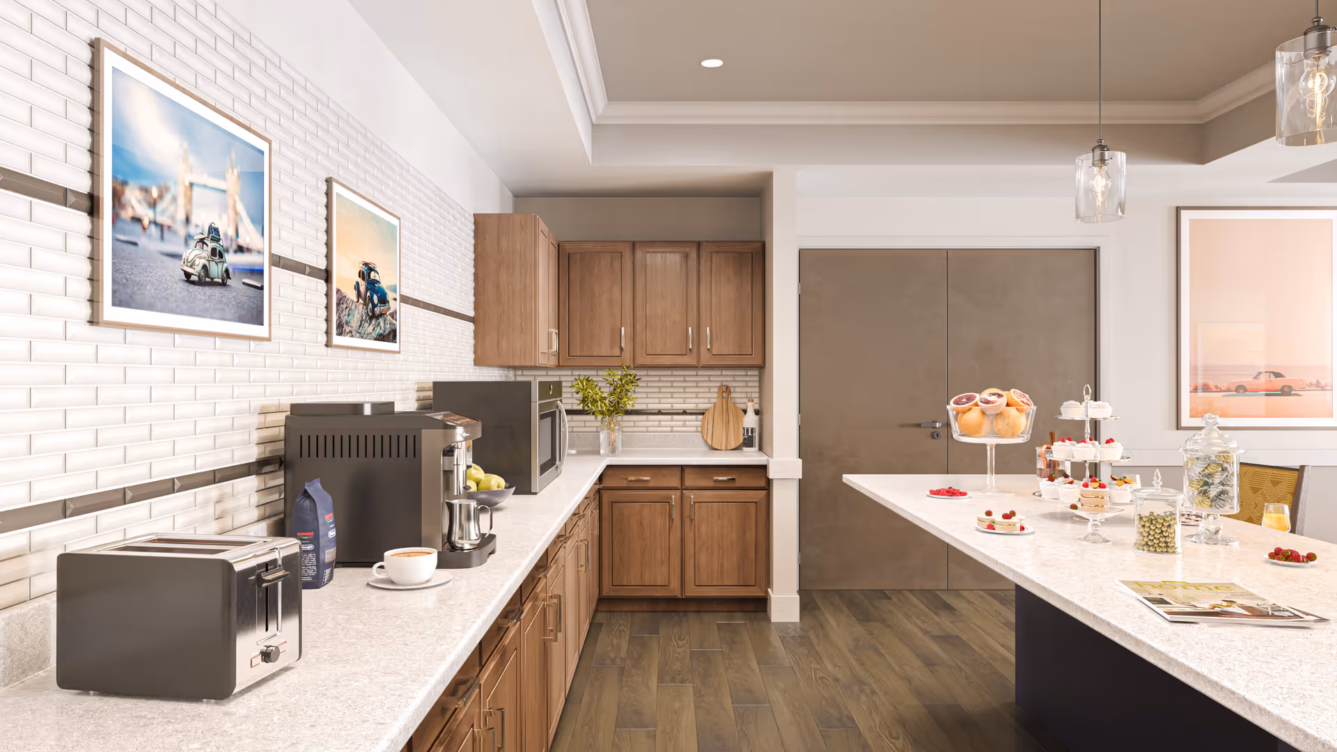 Communal kitchen area with white countertops, wooden cabinets, a toaster and coffee machine on the counter, and an island displaying pastries and glass jars.