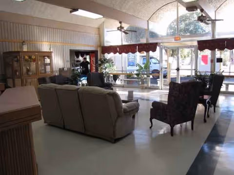 Lounge area in a senior facility with sofas, chairs, and large glass doors.