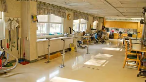 Bright rehab gym inside Meadowbrook at Appleton with parallel bars and exercise equipment.