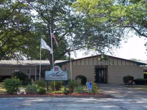 Exterior view of Arcadia Care at Aledo facility with sign and flags in front.