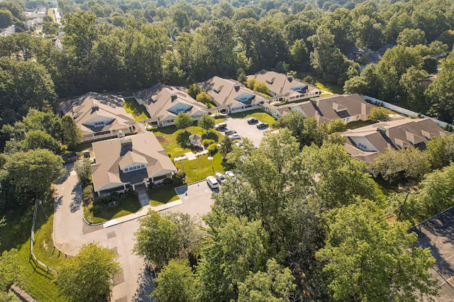 Aerial exterior view of Maple Ridge Senior Living showing multiple single-story residential buildings, parking areas, walkways, and surrounding trees.