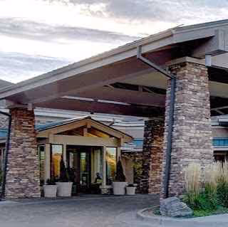 Entrance to Vi at Highlands Ranch with stone columns and potted plants.