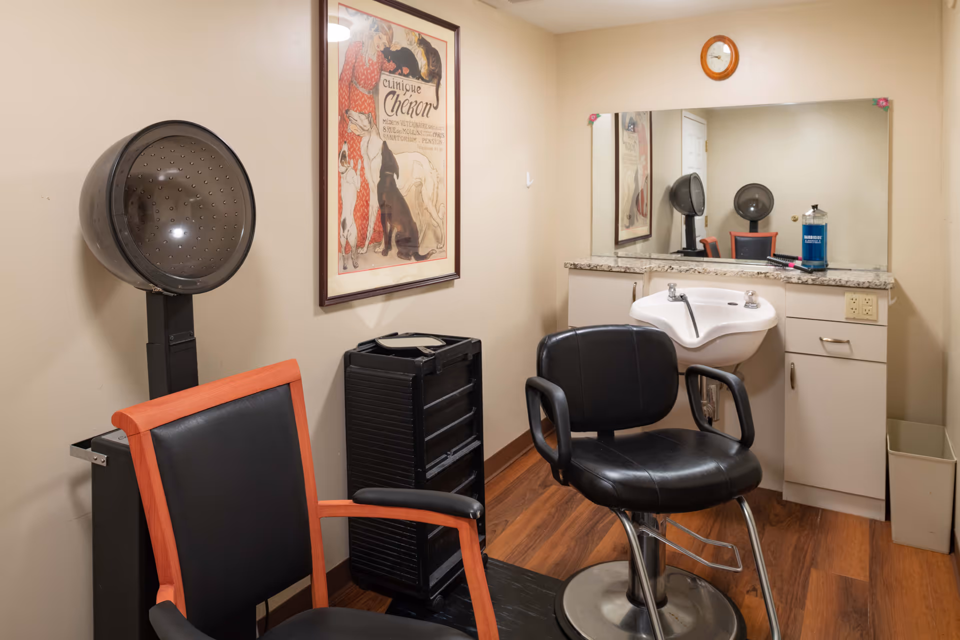 Small salon room with styling chairs, a hooded hair dryer, sink and a large mirror.