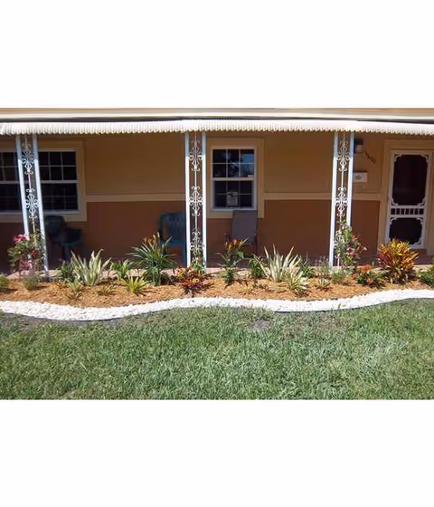 Front porch of a senior living facility with decorative plants and a landscaped garden bed.