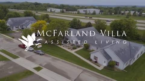 Aerial view of McFarland Villa assisted living buildings, parking lot, and surrounding lawns next to a highway.