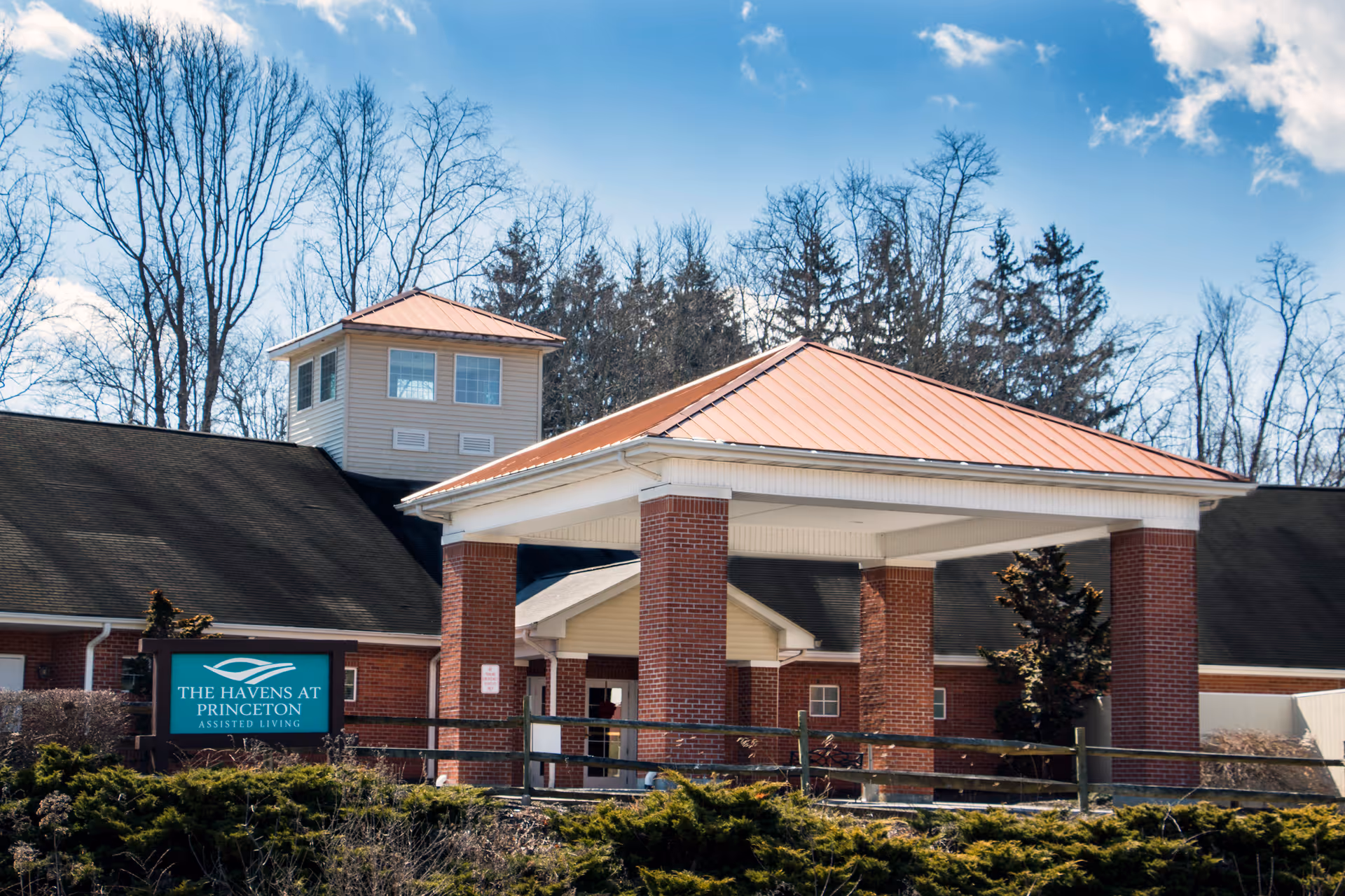 Front entrance of The Havens at Princeton assisted living building with a brick porte-cochere and exterior sign.