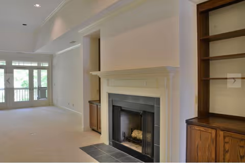 Living room with fireplace, built-in shelves, and glass doors opening to a balcony.