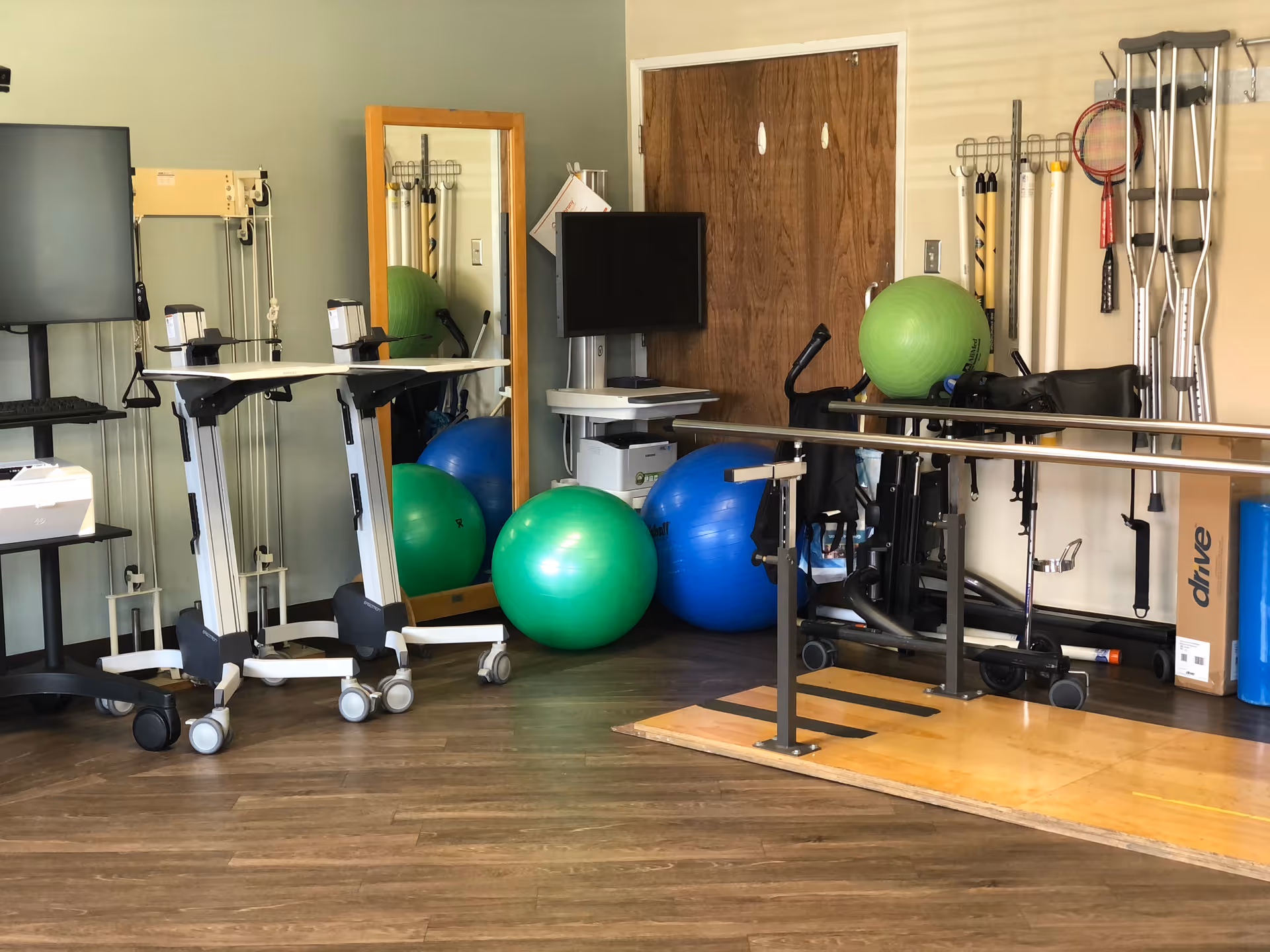 Therapy/exercise room with parallel bars, large exercise balls, rolling carts, crutches and other mobility equipment.