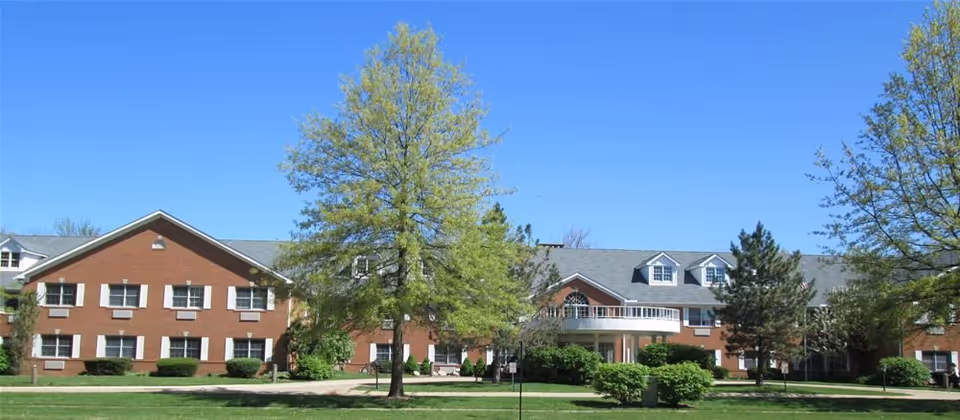 Exterior view of Liberty Residence Independent Living building with brick facade, trees, and clear blue sky.