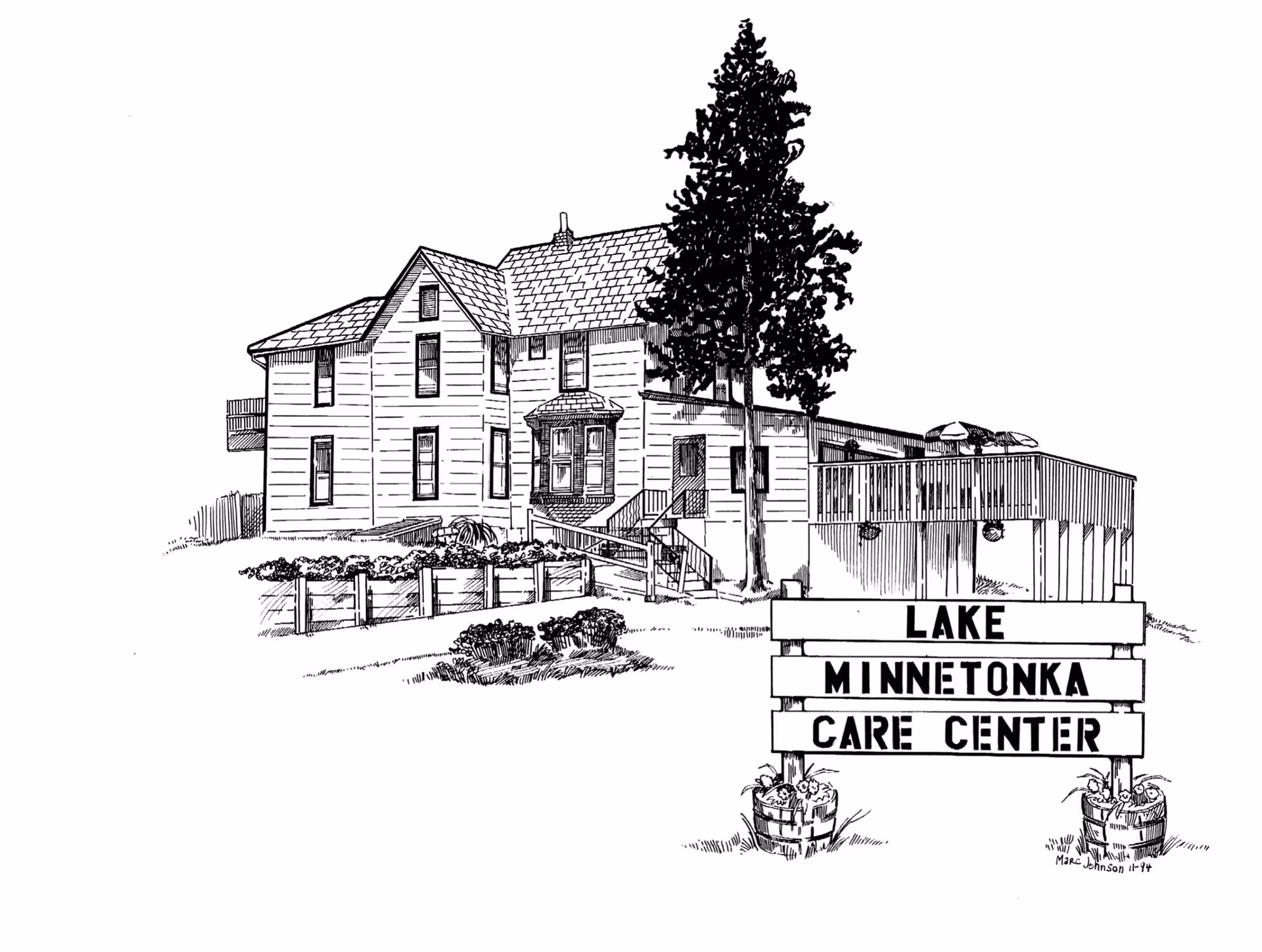 Black and white line drawing of a two-story building with a pitched roof, surrounded by landscaping and a large tree. In front of the building is a sign that reads 'Lake Minnetonka Care Center' with flower pots at the base.