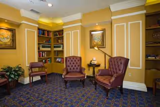 Cozy seating area with two tufted chairs, lamps, and built-in bookshelves.