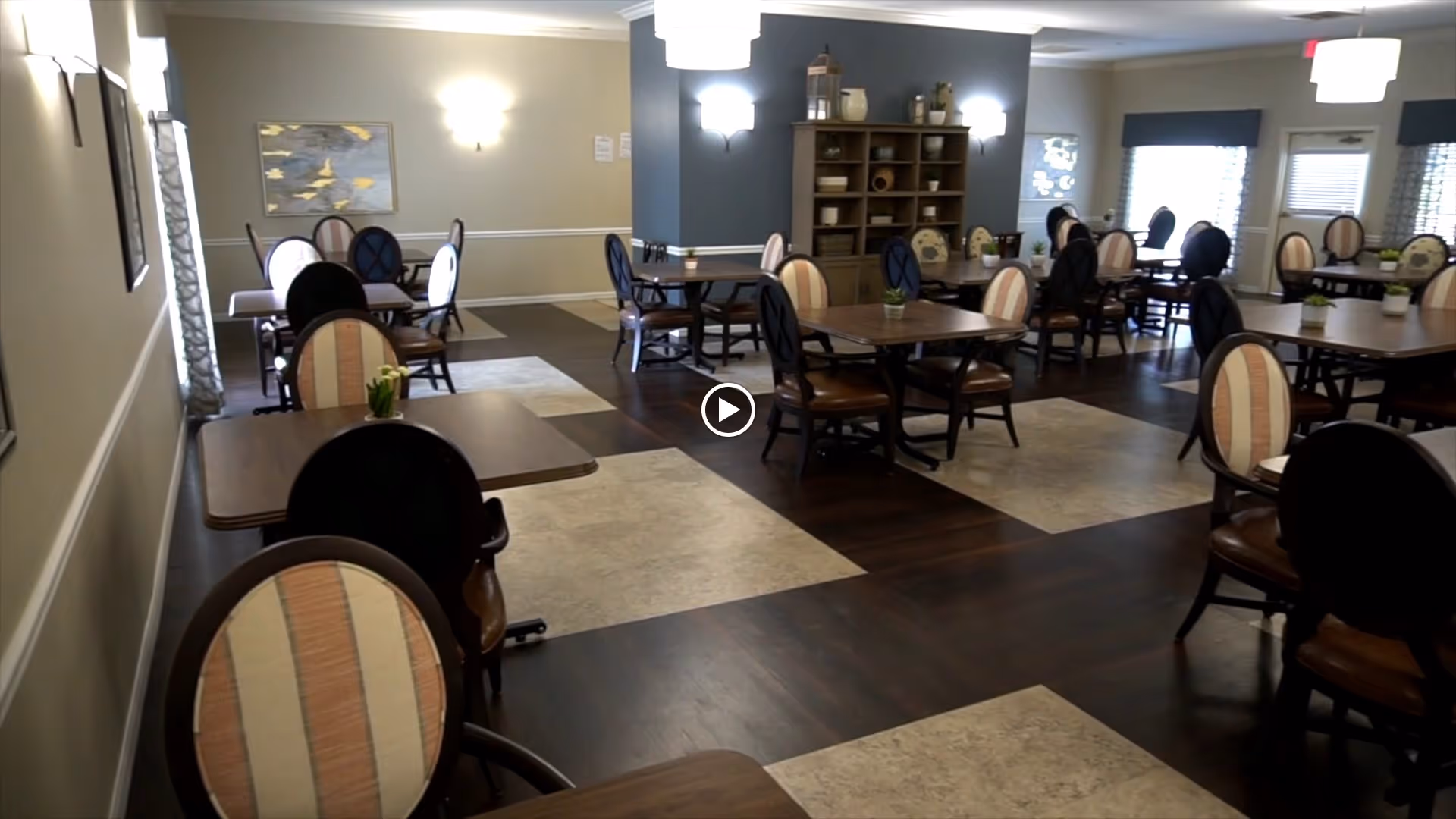 Spacious dining room with multiple tables and upholstered chairs arranged on a patterned wood floor.
