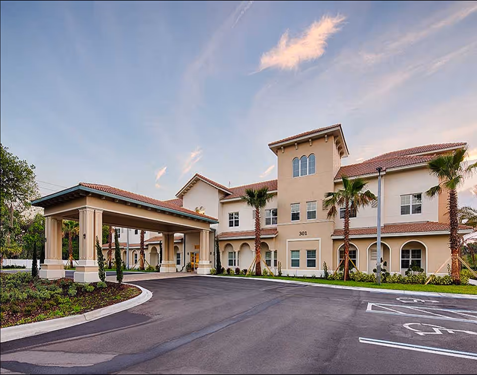 Exterior view of Lexington Place senior living facility with covered entrance and palm trees.