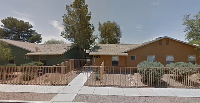Single-story assisted living building with green and tan exterior and front walkway.