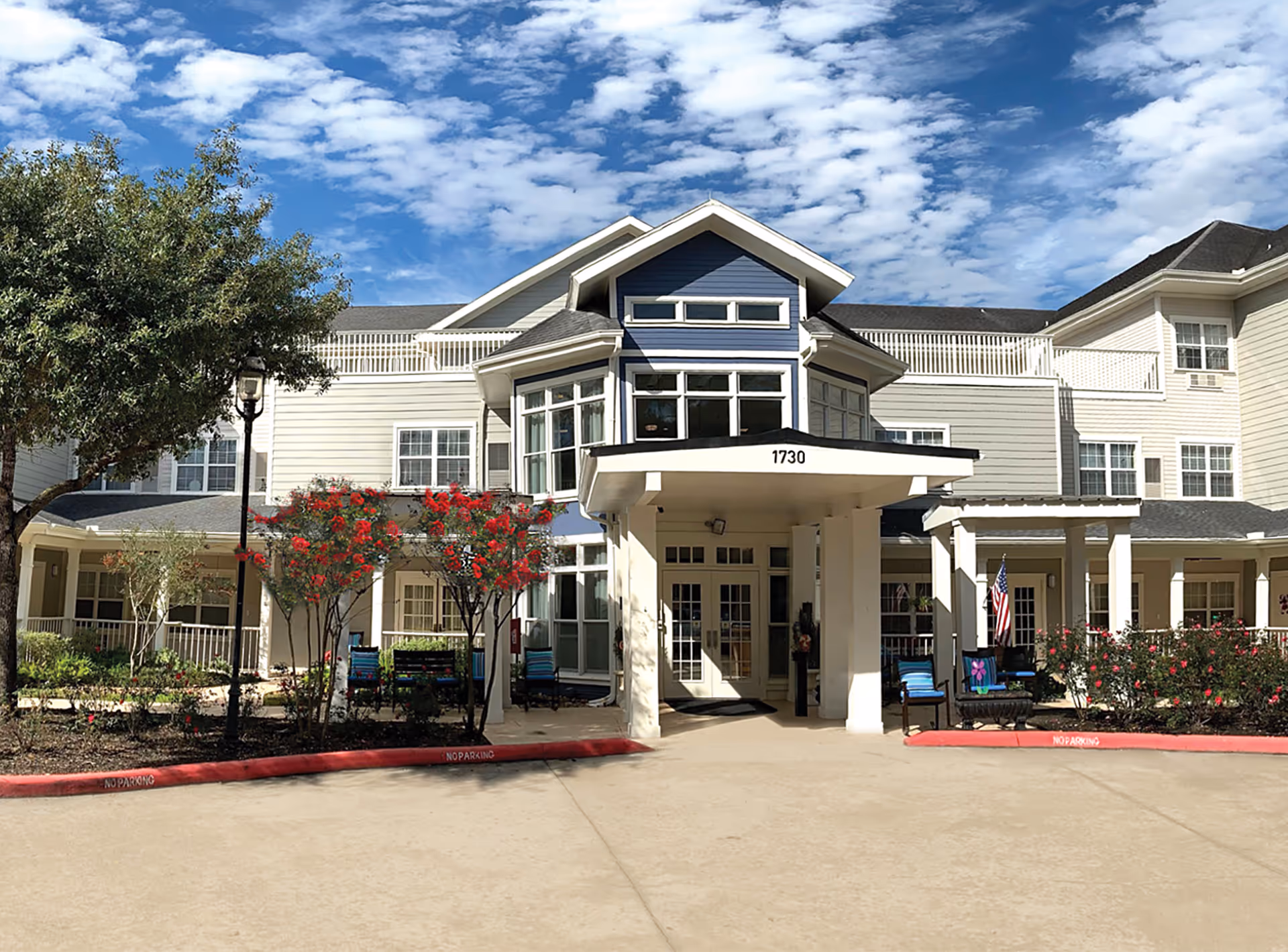 Front entrance of a multi-story senior living facility with a covered porte-cochere, landscaping, and the address number 1730.