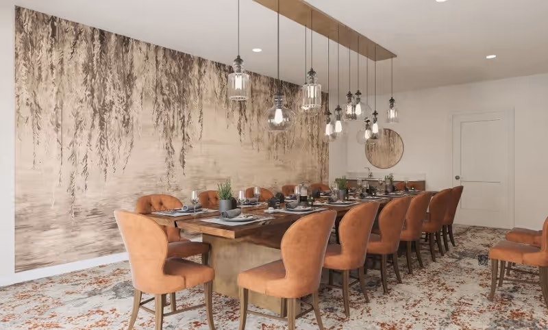A long dining room with a wooden table set for many guests, upholstered orange chairs, hanging pendant lights, and a large mural on the wall.