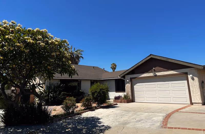Front exterior of a single-story house with a two-car garage and landscaped yard.