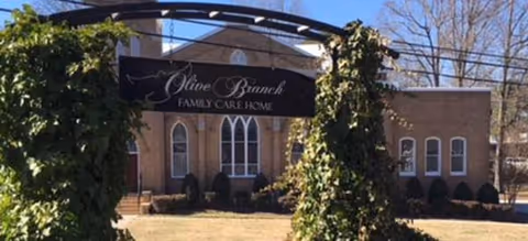 Brick building facade of Olive Branch Family Care Home with arched windows