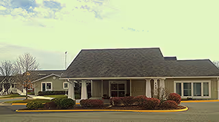 Front view of Green Valley Commons Assisted Living with shrubs and parking