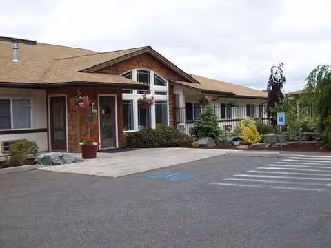 Single-story senior living facility exterior featuring entrance, parking lot, and landscaped front.
