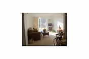 Cozy living room with seating, coffee table, and a large sunny window.