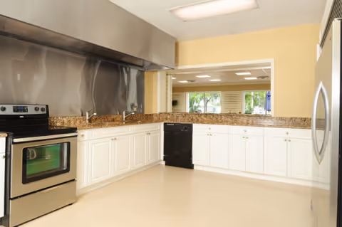 Bright kitchen with white cabinets, granite countertops, and stainless steel appliances.
