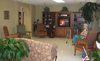 Cozy senior living room with couches, plants, and a TV unit.