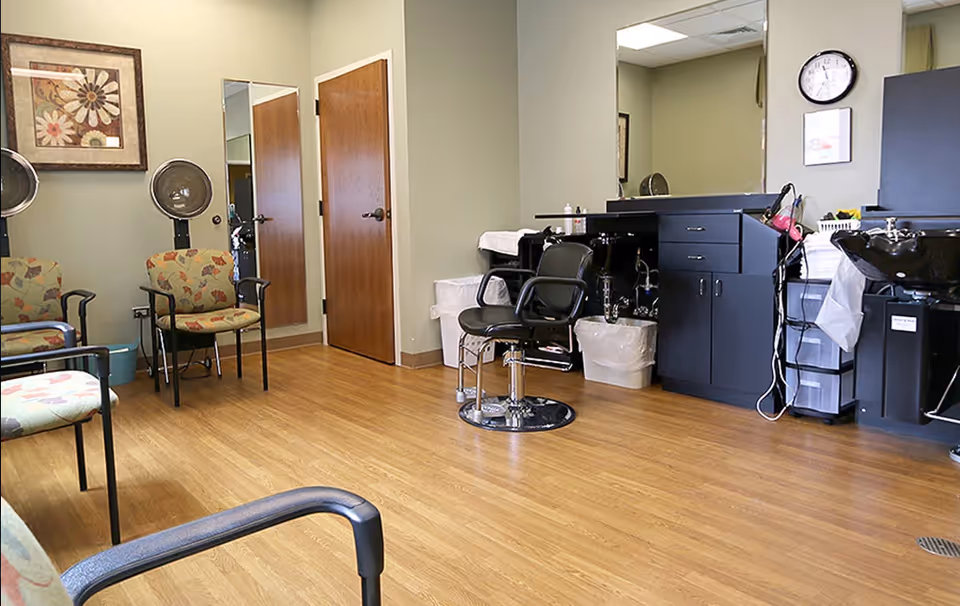 Hair styling chairs, mirrors, and supplies arranged in a clean senior living salon.