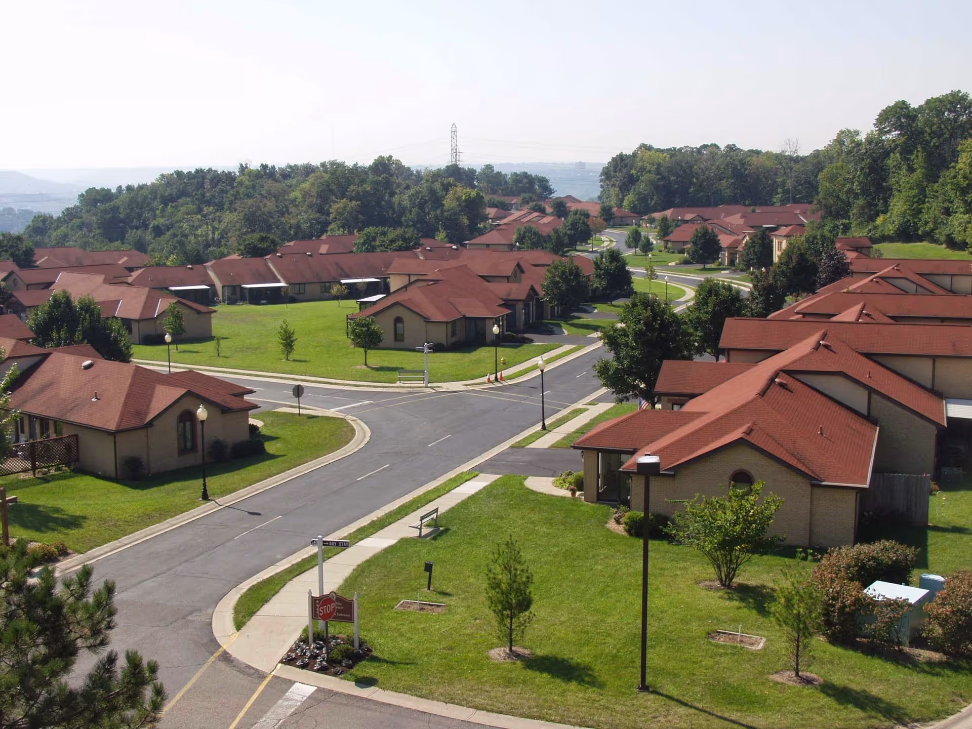 Aerial view of a residential community of single-story, red-roofed buildings with roads, sidewalks, and green lawns.