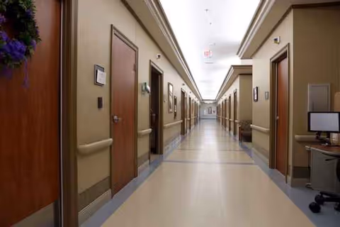 Long beige interior hallway in a senior living facility with closed doors.