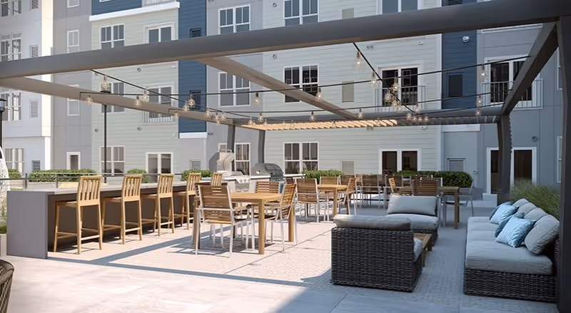 Outdoor courtyard patio with a pergola and string lights, featuring dining tables, bar seating, a grill, and lounge furniture in front of an apartment building.