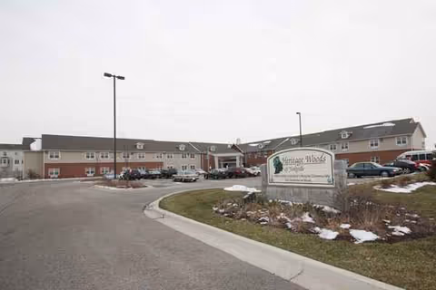 Exterior view of Heritage Woods of Yorkville with parked cars and a sign.