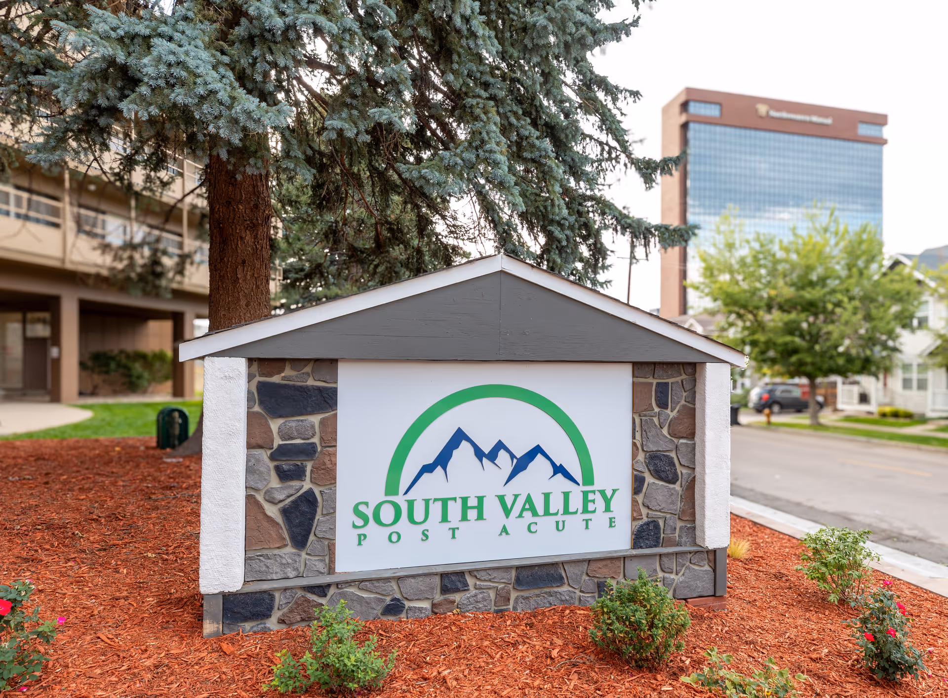 Sign for South Valley Post Acute Rehabilitation surrounded by landscaping and trees.