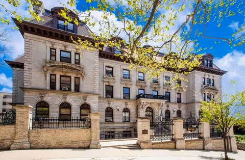 Sunlit stone senior living building facade with arched windows and decorative balconies