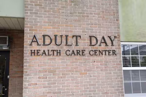 Brick exterior wall with 'ADULT DAY HEALTH CARE CENTER' sign and doorway.