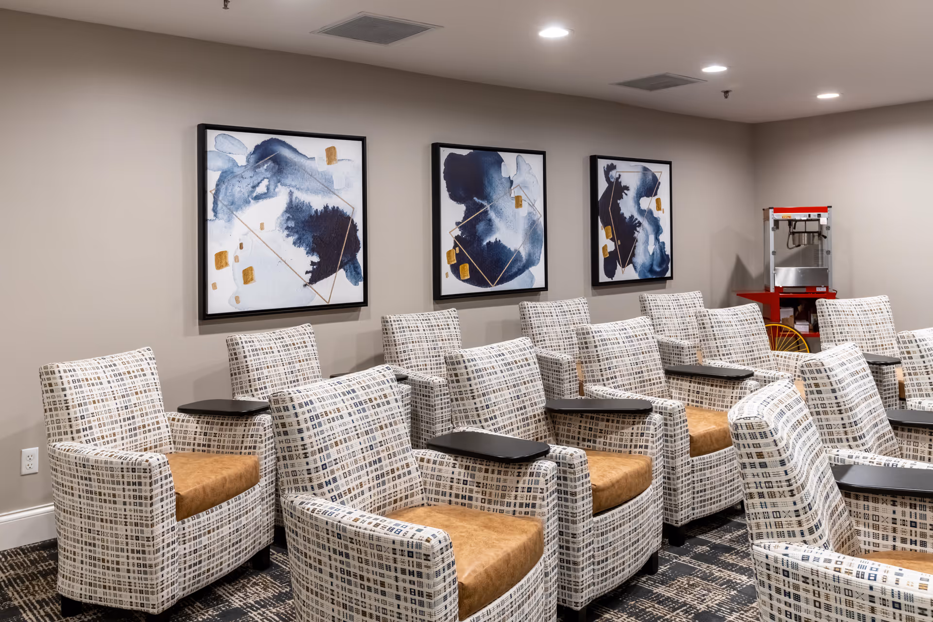 Lounge area with rows of patterned armchairs, art on the walls, and a red service cart.