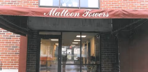 Brick building entrance with Mattoon Towers sign and glass doors leading to a lobby