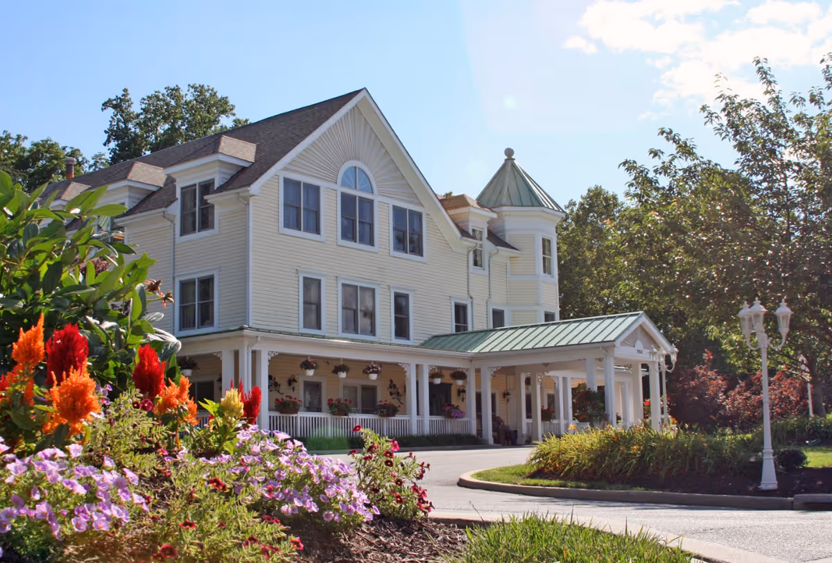 Sunny exterior of Seaton Towson's large, light-yellow building with a covered entrance and garden.