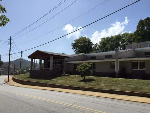 Exterior view of Haywood House senior living facility with a covered entrance and lawn