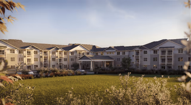 Three-story senior living building with a covered entrance and balconies overlooking a landscaped lawn.